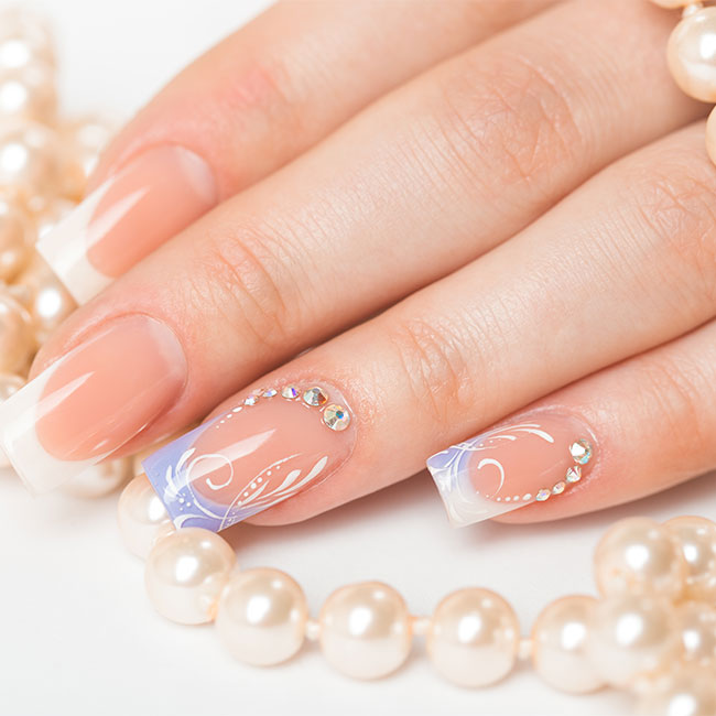 French acrylic nails with hand-painted lilac art and crystals beside pearls